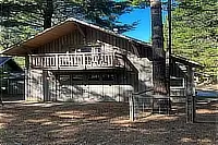 Exterior of The Boat House surrounded by tall trees, with an upper-level balcony.
