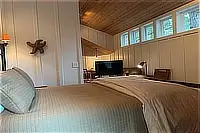 Queen bed beneath high windows and a sloped wood ceiling.