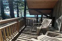 Wooden balcony with outdoor chairs overlooking the surrounding trees.
