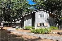 Side exterior of the two-story house with trees and landscaped grounds.
