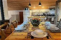 Dining table set for a meal beside the kitchen and living area.