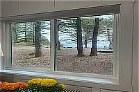 View of coastal trees and the ocean through a large window.