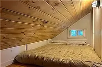 Cozy sleeping alcove beneath a sloping wooden ceiling.