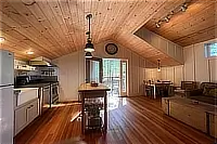 Kitchen and dining area with wood cabinetry, vaulted ceiling, and hardwood floors.