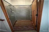 Shower enclosure with glass door and tiled interior.