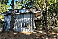 Exterior view of The Boat House with balcony and surrounding trees.