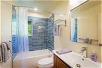 Bathroom with bathtub, tiled shower surround, and vanity