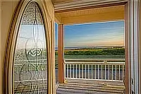 View of the ocean and coastline through an open doorway leading onto the balcony.