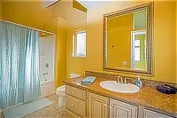 Bathroom vanity with granite countertop, white sink, framed mirror, and shower curtain.
