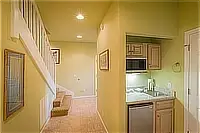 Interior hallway with staircase and a small kitchenette featuring a sink and microwave.
