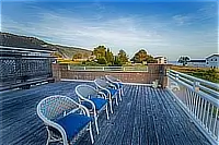 Spacious wooden deck with outdoor chairs overlooking the surrounding coastal neighborhood.