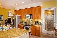Kitchen with granite breakfast bar, wooden cabinetry, and stainless steel appliances.
