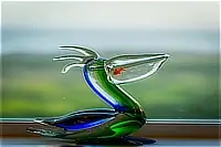 Colorful glass pelican sculpture displayed on a windowsill with a blurred coastal background.